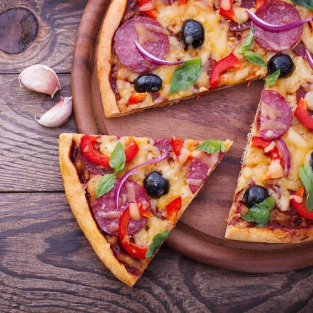 Pizza with ham, pepper and olives. Delicious fresh pizza served on wooden table.の写真素材