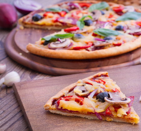 Pizza with ham, pepper and olives. Delicious fresh pizza served on wooden table.の写真素材
