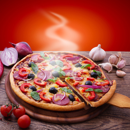 Pizza with ham, pepper and olives. Delicious fresh pizza served on wooden table.の写真素材