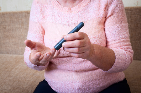 Woman testing for high blood sugar. Woman holding device for measuring blood sugarの写真素材