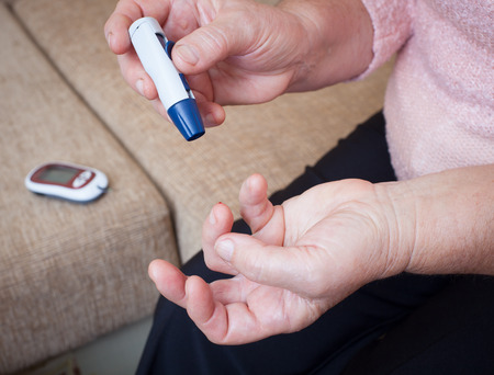 Woman testing for high blood sugar. Woman holding device for measuring blood sugarの写真素材