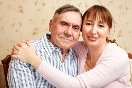 Happy family. Portrait of elderly couple and adult daughter happily looking at camera. Senior man, woman with their caregiver at home.の写真素材