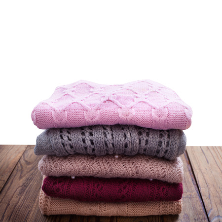 Knitting clothes stacked on wooden background. Concept delicate care of woolen clothes.の写真素材