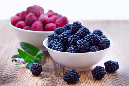 Bowls overflowing with summer berries like raspberries and blackberries closeup.の写真素材