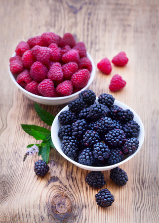 Bowls overflowing with summer berries like raspberries and blackberries closeup.の写真素材