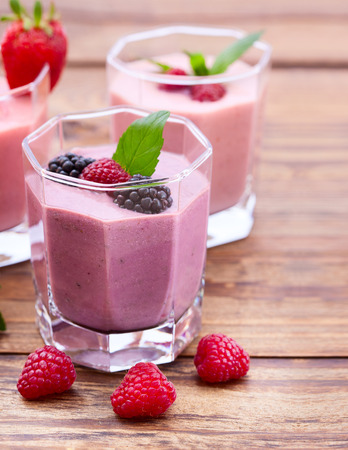 Drink smoothies four summer strawberry, blackberry, kiwi, raspberry on wooden table closeup.の写真素材