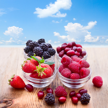 Bowls overflowing with summer berries like raspberries and blackberries closeup.の写真素材