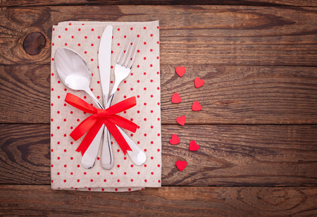 Valentines dinner on wooden background. Table setting for Valentines Day. fork, knife and red heartsの写真素材