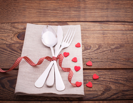 Valentines dinner on wooden background. Table setting for Valentines Day. fork, knife and red heartsの写真素材