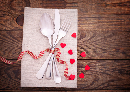 Valentines dinner on wooden background. Table setting for Valentines Day. fork, knife and red heartsの写真素材
