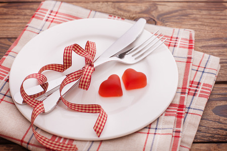 Valentines dinner on wooden background. Table setting for Valentines Day. fork, knife and red heartsの写真素材