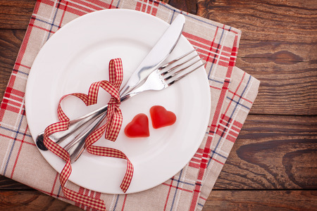 Valentines dinner on wooden background. Table setting for Valentines Day. fork, knife and red heartsの写真素材
