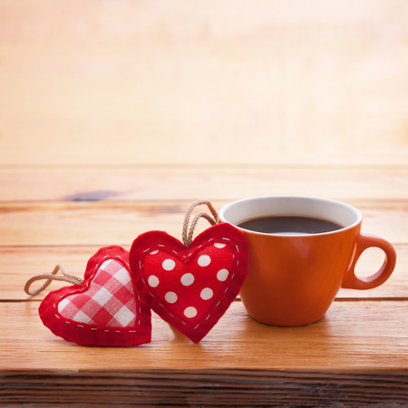 Cup of coffee and handmade heart of fabric on wooden table on Valentines Day . Love recognition.の写真素材