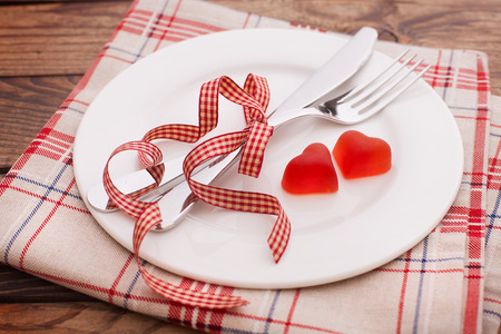Valentines dinner on wooden background. Table setting for Valentines Day. fork, knife and red heartsの写真素材