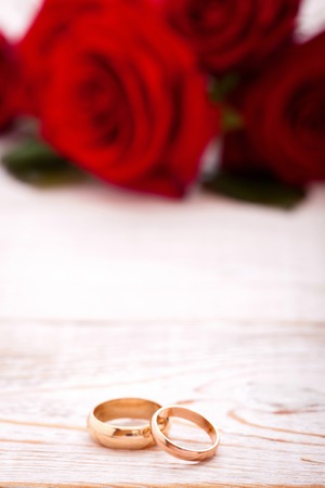 Wedding rings and wedding bouquet of red roses on wooden table. horizontallyの写真素材