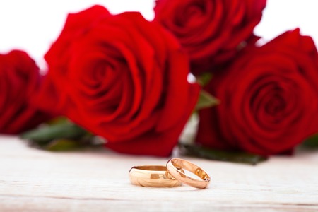 Wedding rings and wedding bouquet of red roses on wooden table. horizontallyの写真素材