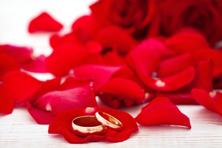 Wedding rings and wedding bouquet of red roses on wooden table. horizontallyの写真素材
