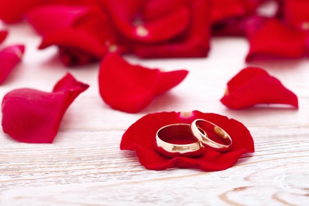Wedding rings and wedding bouquet of red roses on wooden table. horizontallyの写真素材
