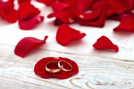 Wedding rings and wedding bouquet of red roses on wooden table. horizontallyの写真素材