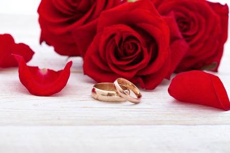 Wedding rings and wedding bouquet of red roses on wooden table. horizontallyの写真素材