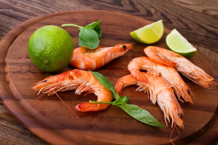 Delicious fresh seafood shrimp with lime on wooden table closeup top view horizontalの写真素材