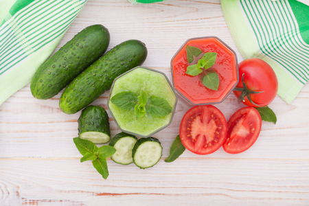 Tomato, cucumber Juices and vegetables on white wooden table top viewの写真素材