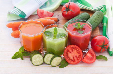 Tomato, cucumber, carrot Juices and vegetables on white wooden table top viewの写真素材