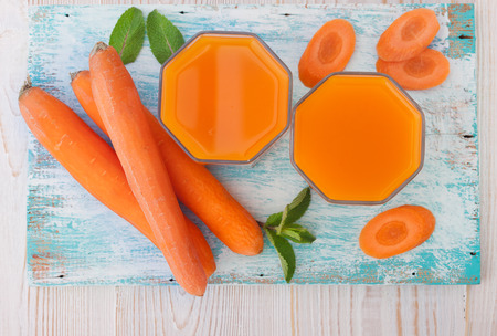 Carrot Juices and vegetables on white wooden table top viewの写真素材