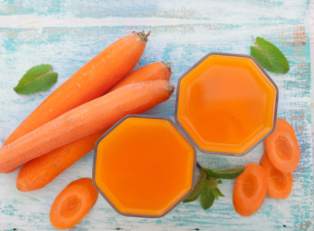 Carrot Juices and vegetables on white wooden table top viewの写真素材