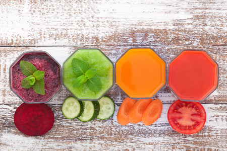 Tomato, cucumber, carrot, beet Juices and vegetables on white wooden table top view.の写真素材
