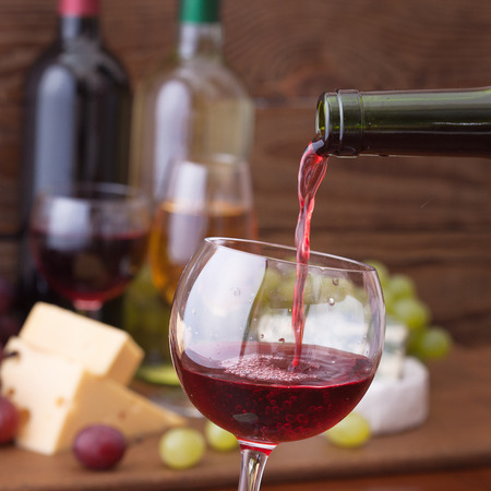 Red wine pouring into wine glass, close-up. Flat mock up for design.の写真素材