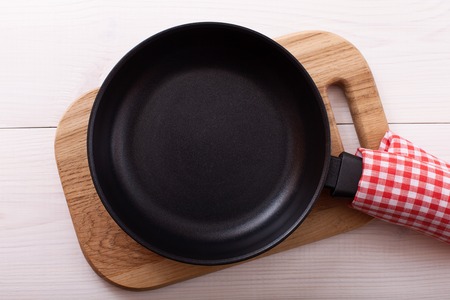 Empty pan on wooden deck table with tablecloth. Flat mock up for design. Top view.の写真素材
