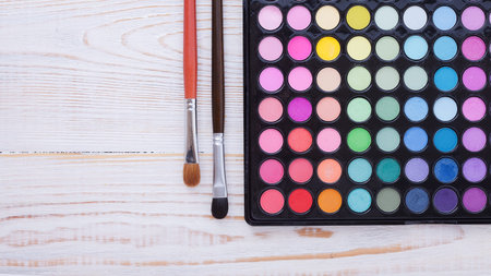 Colorful frame with various makeup products on white wooden backgroundの写真素材