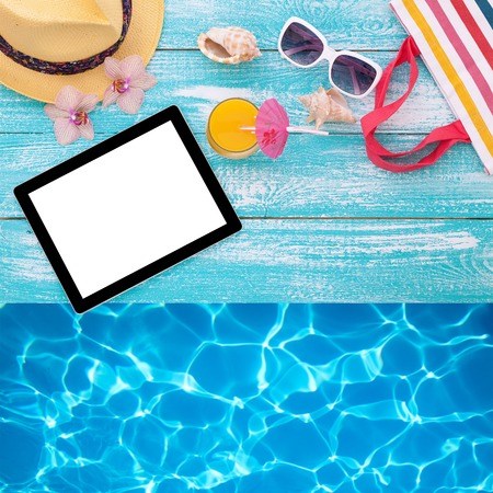 Blank empty tablet computer on beach. Trendy summer accessories on wooden background pool. Sunglasses, orange juice and flip-flops on beach. Tropical flower orchid. Flat mock up for design.の写真素材