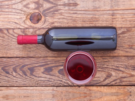 Glass and bottle of red wine. Flat mock up for design unusually on wooden background.の写真素材