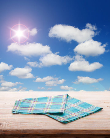 Empty table and tablecloth, Blue summer sky with clouds as a background, for product display montage