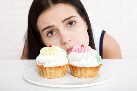 Woman with cake close-up face. Beautiful women sadly looks at cake . Asian woman.の写真素材