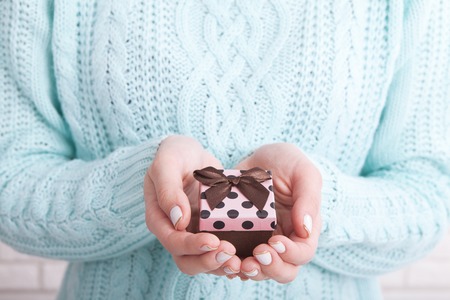 Female hands holding small gift with ribbon.の写真素材