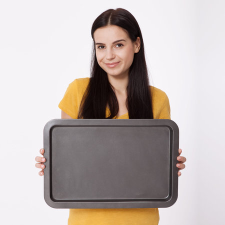 Young attractive woman holding an empty tray on white background.の写真素材