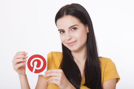 KIEV, UKRAINE - AUGUST 22, 2016: Woman hands holding Pinterest icon printed paper. Is photo sharing...