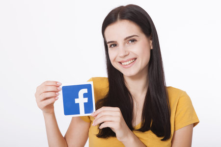KIEV, UKRAINE - August 22, 2016: Woman hands holding facebook icon sign printed on paper on white...