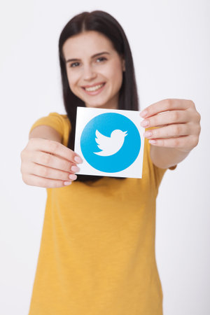 KIEV, UKRAINE - AUGUST 22, 2016: Woman hands holding Twitter logotype icoi bird printed paper. Twitter is an online social networking service that enables users to send and read short messages.のeditorial素材