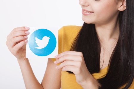 KIEV, UKRAINE - AUGUST 22, 2016: Woman hands holding Twitter logotype icoi bird printed paper. Twitter is an online social networking service that enables users to send and read short messages.のeditorial素材