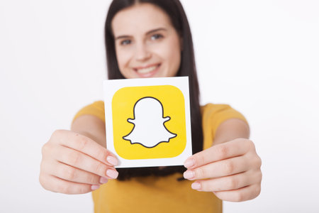 Kiev, Ukraine - August 22, 2016:Woman Hands holding Snapchat logo icon printed on paper. Snapchat is a popular social media application for sharing messages, images and videosのeditorial素材