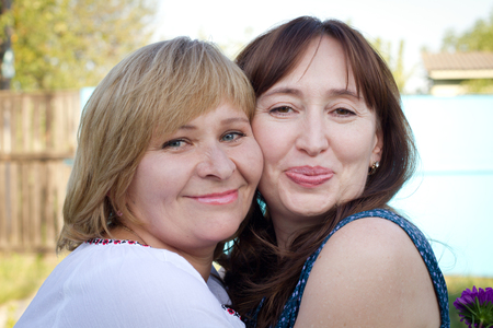 Happy women talking and laughing in nature with a green backgroundの写真素材
