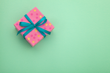 Craft paper pink gift box with as a present for Christmas, new year, valentine day or anniversary on green background, top view, mock upの写真素材