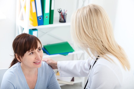 Female patient being reassured by doctor in hospital.の写真素材