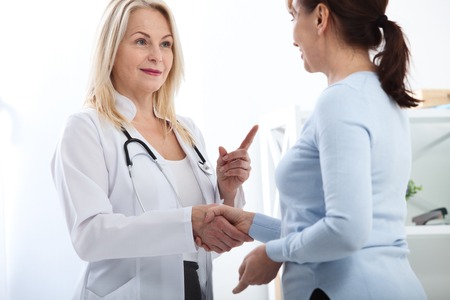Healthcare and medical concept - doctor with patient in hospital. Handshake.の写真素材
