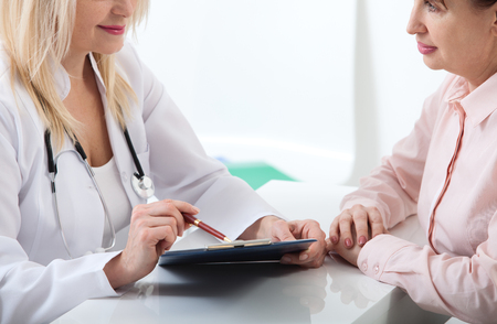Female doctor holding application form while consulting patient at hospitalの写真素材