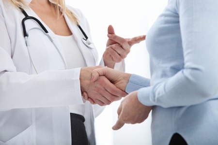 Healthcare and medical concept - doctor with patient in hospital. Handshake.の写真素材